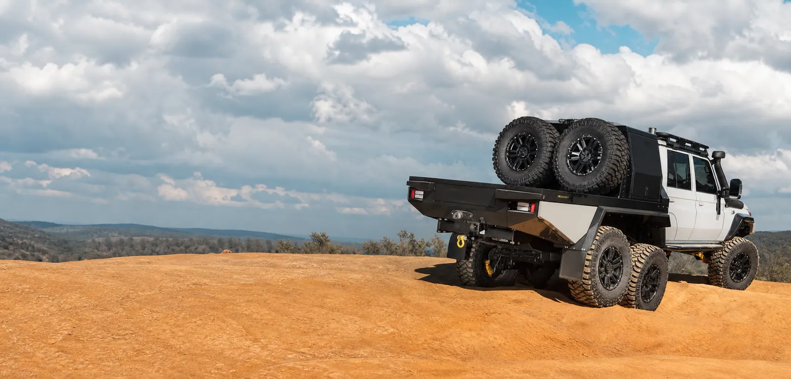 JMACX 6x6 Land Cruiser 79 with tandem rear axles on a rugged trail