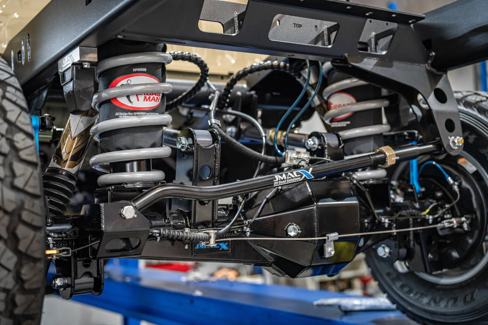 JMACX rear coil conversion fitted under a Land Cruiser 79: coil springs, trailing arms, panhard rod and wide-track differential housing