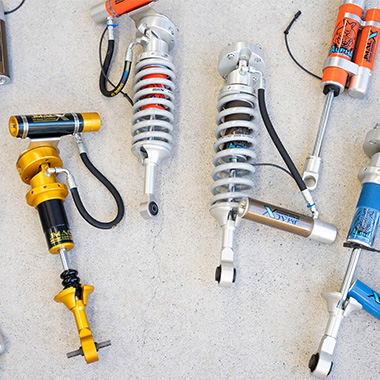 Range of JMACX Alpha adjustable shocks with remote reservoirs laid out on concrete